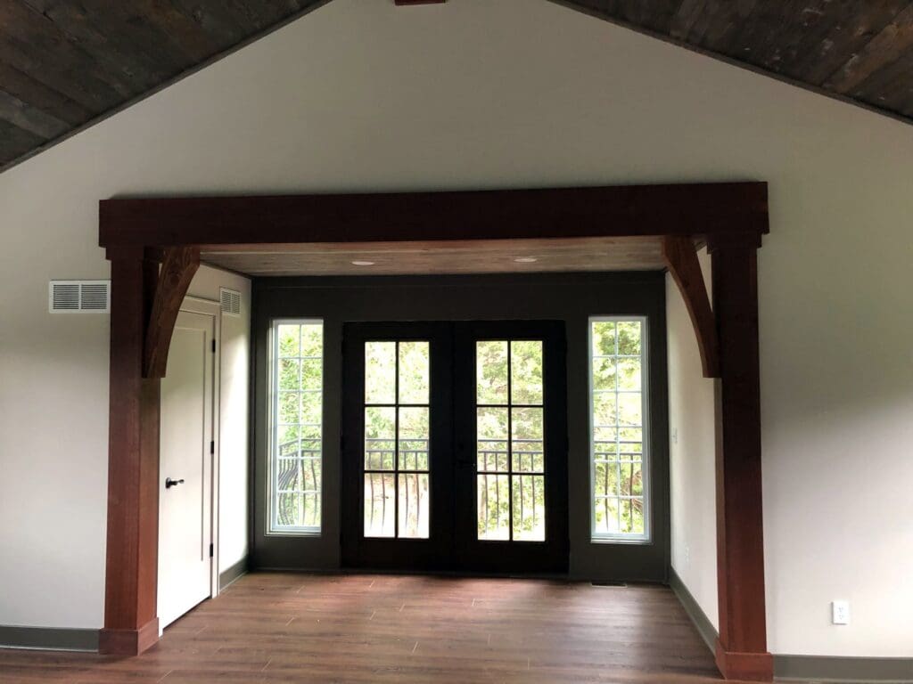 Darker stained, thick lumber nicely accents a large opening to a separate interior area of the house