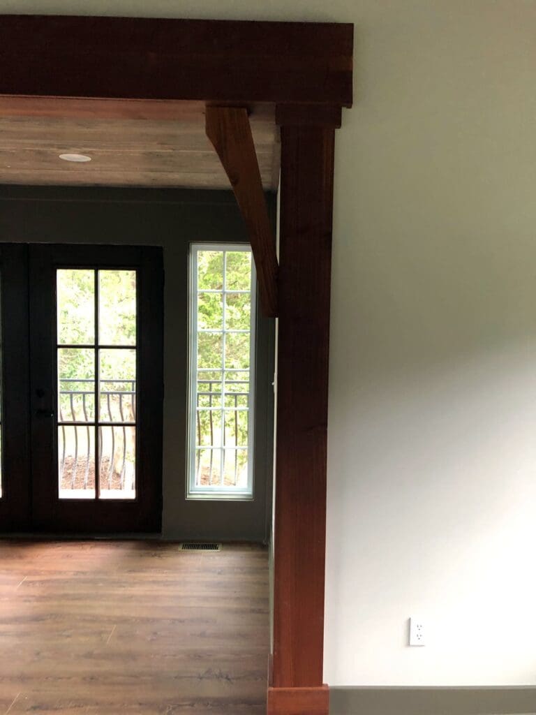 Light from outdoors shines indoors, highlighting the edge of the custom wood that adorns a passageway