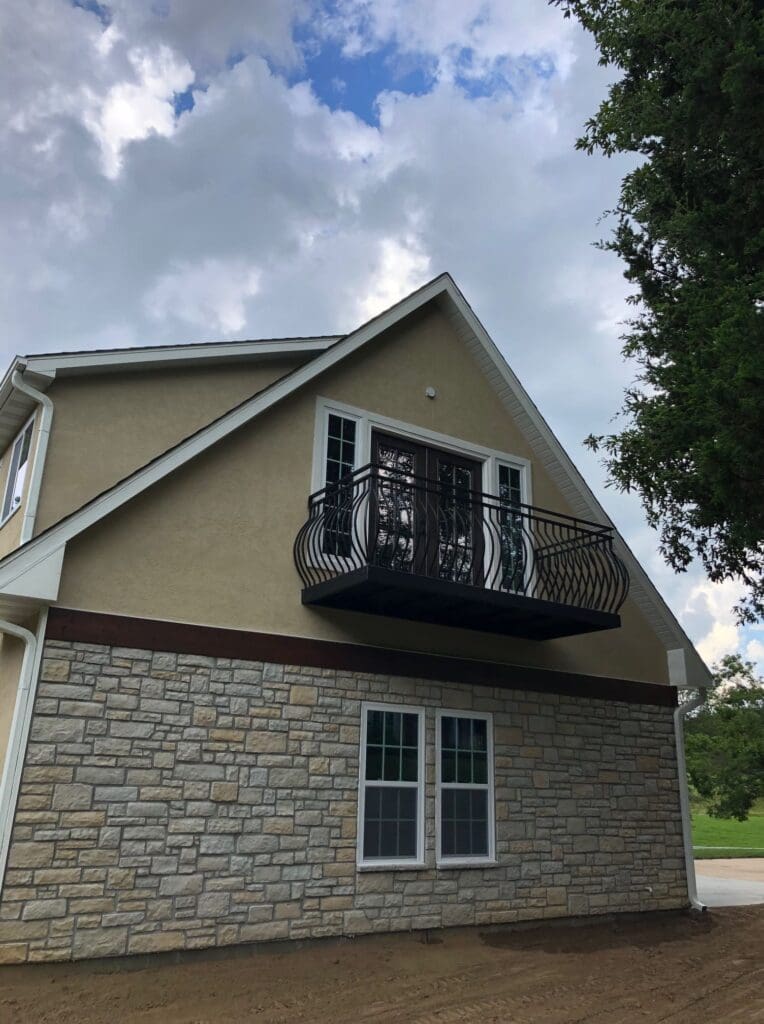 A custom project has rendered a dark metal balcony railing that has a convex curve to the bars.
