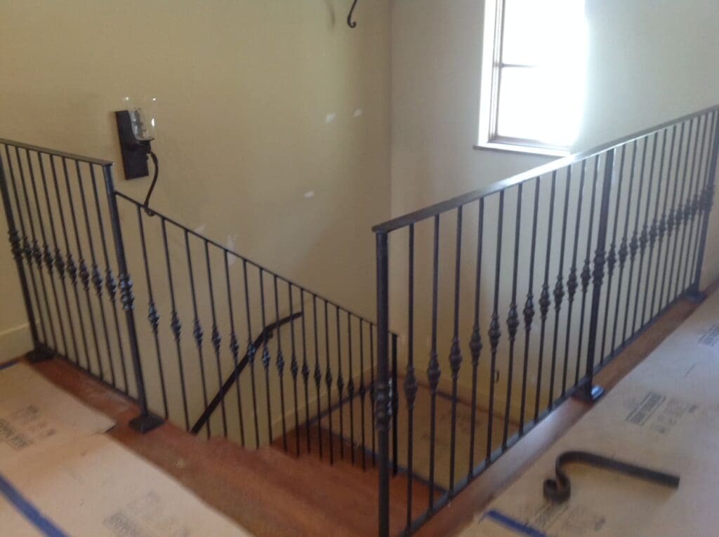 Wrought iron railing lines the second floor, indoor stair area of a two story house