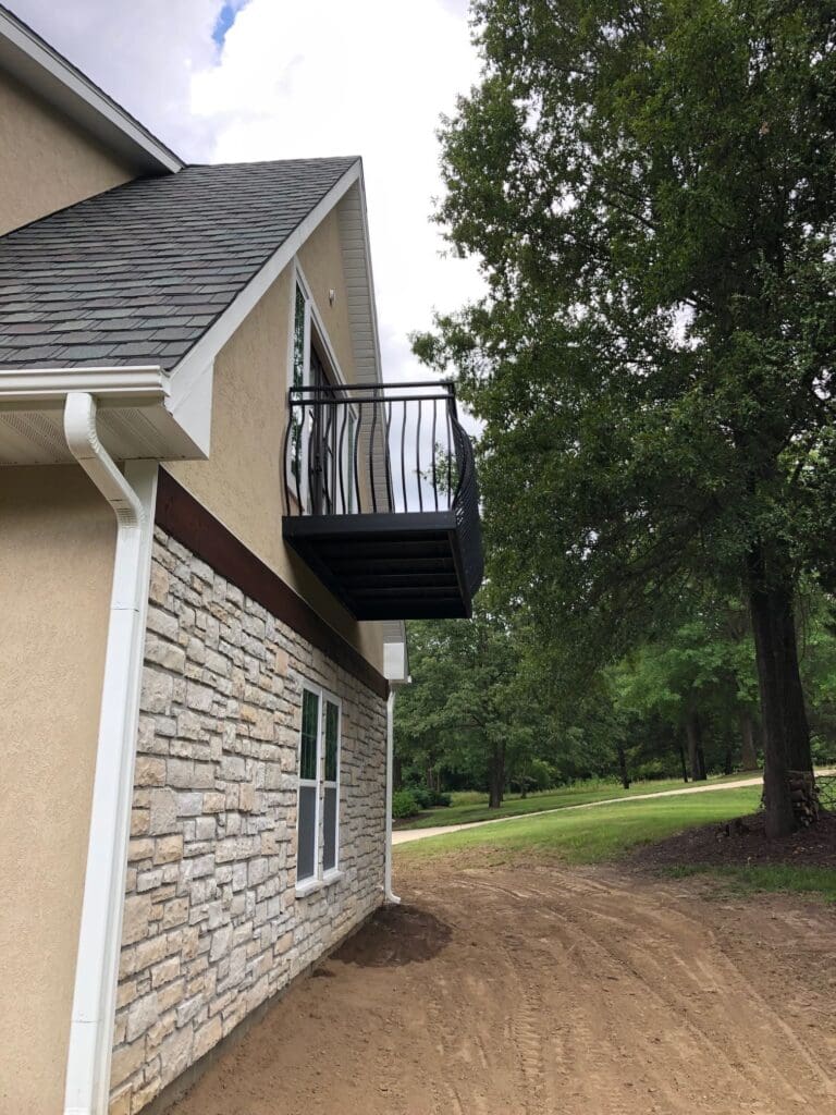 A second outdoor view from ground level revealing a dark metal balcony railing with convex rails