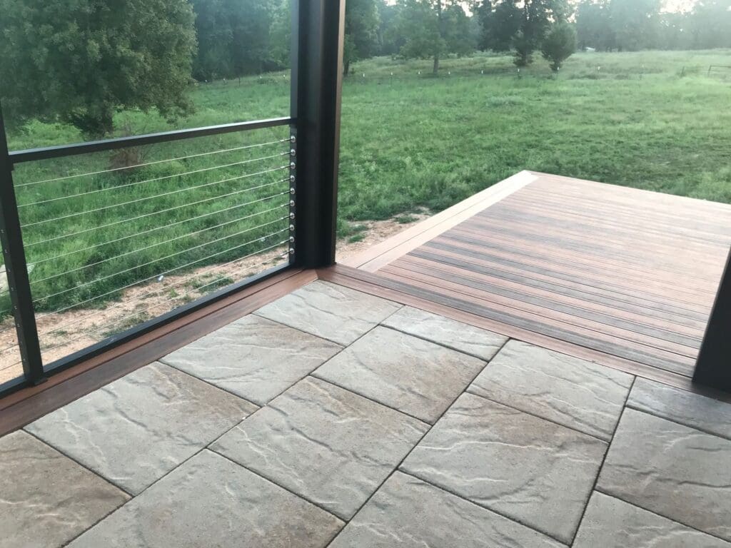 A patio area's tile flooring is outlined by the same wood that's been used for the adjoining sunburst-inspired deck that extends from the patio