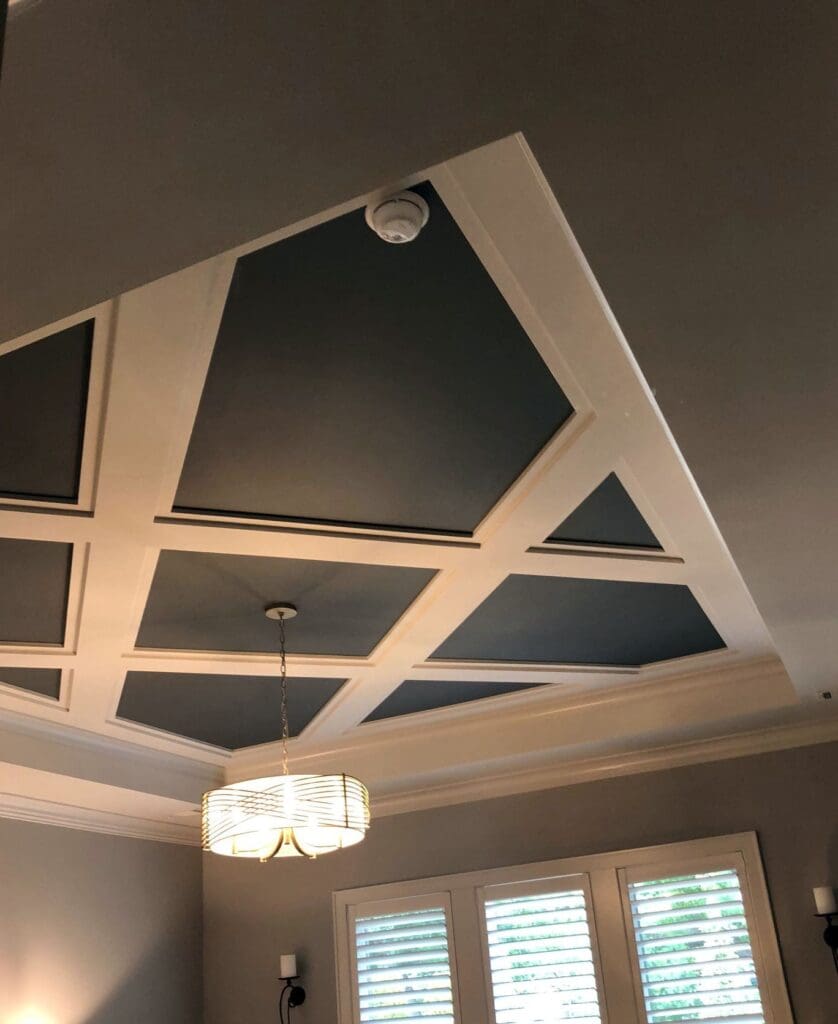 Light beams with complementary moulding create a diagonal lattice pattern against a dark painted ceiling