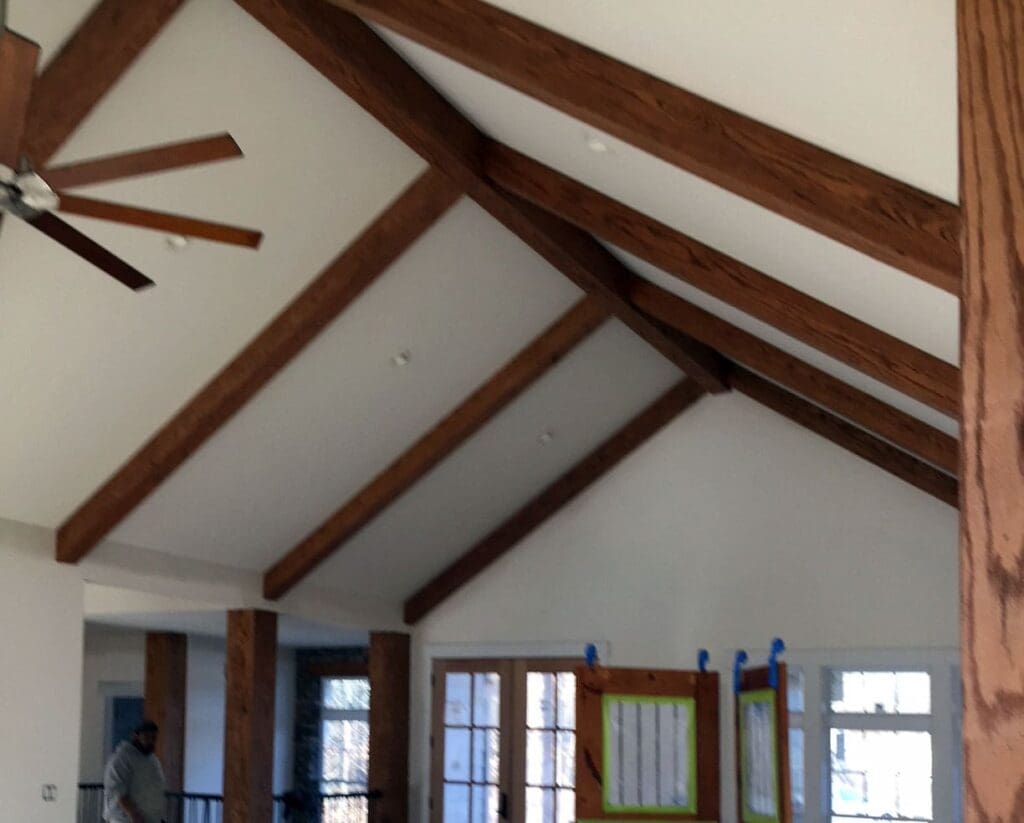 A cottage feel has been created from a large wooden beam spanning across a vaulted ceiling with shorter beams meeting at the center throughout